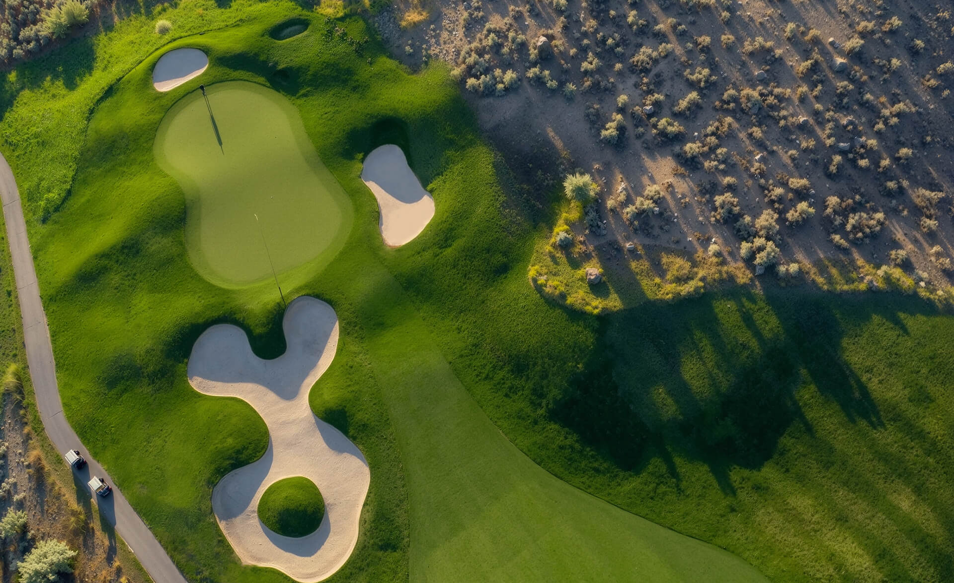 Aerial top-down view of Bighorn Golf Course green with sculpted bunkers, fairway contours, and desert hillside contrast