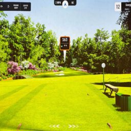 Gemini said An aerial view of two golfers walking across a sunlit green toward a yellow flag, with deep shadows stretching across the grass and a large sand bunker visible in the lower foreground.