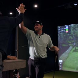 Golfers celebrating with a high five after a successful shot in indoor golf simulator lounge