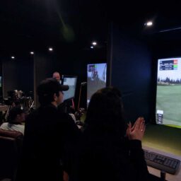 Group enjoying indoor golf simulator experience with virtual course display and social atmosphere