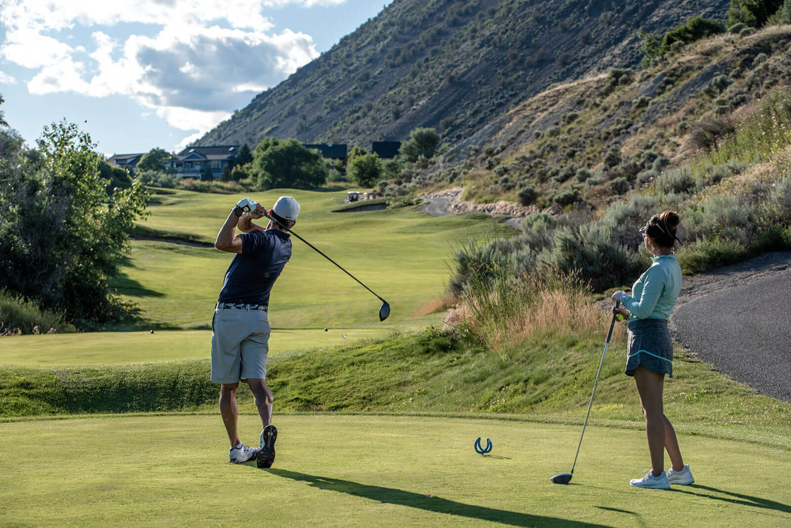 Golfers teeing off at Bighorn Golf Kamloops with rolling fairway and hillside landscape in the background