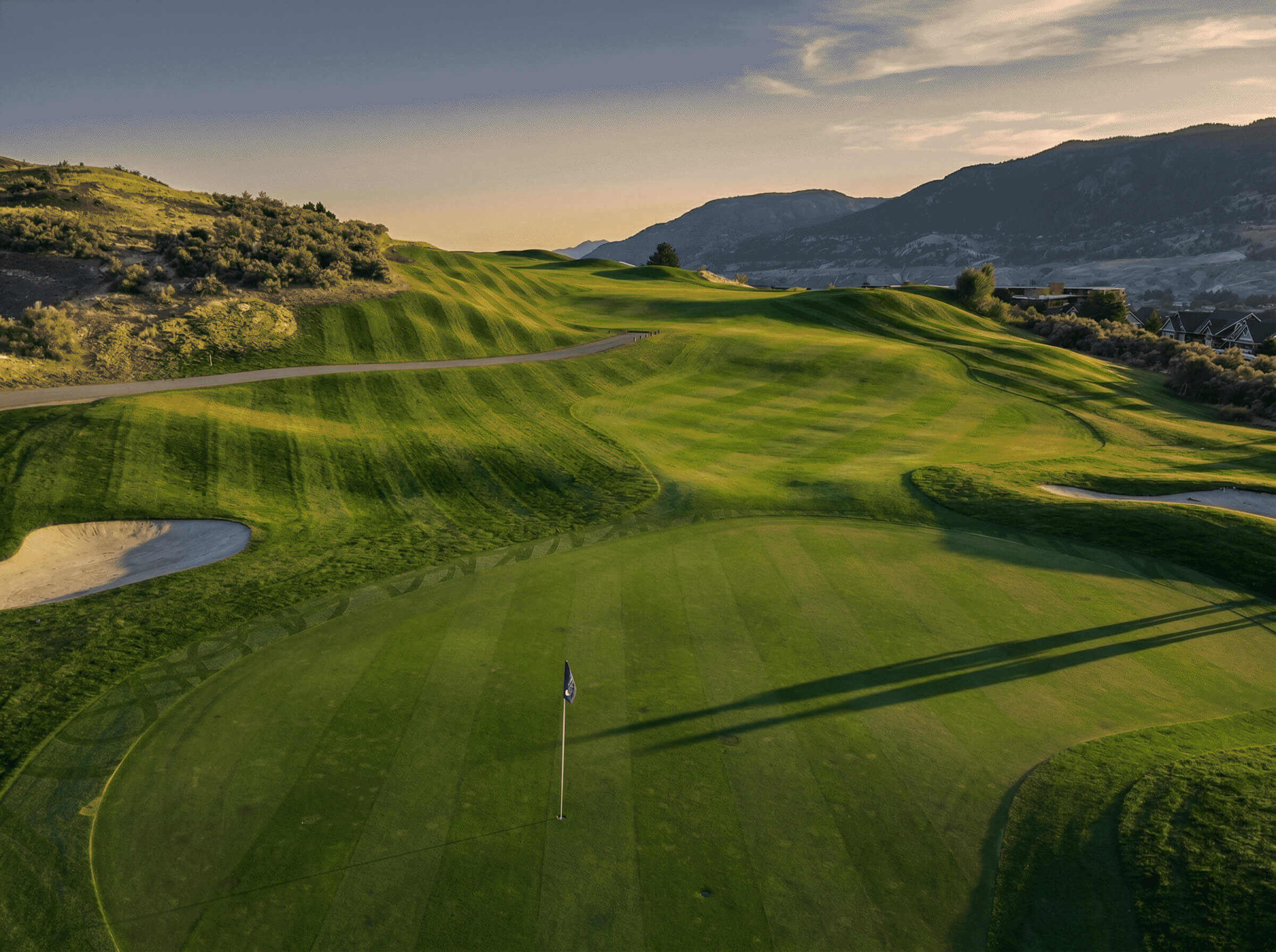 Elevated view of Bighorn Golf Kamloops green and rolling fairway contours with long evening shadows