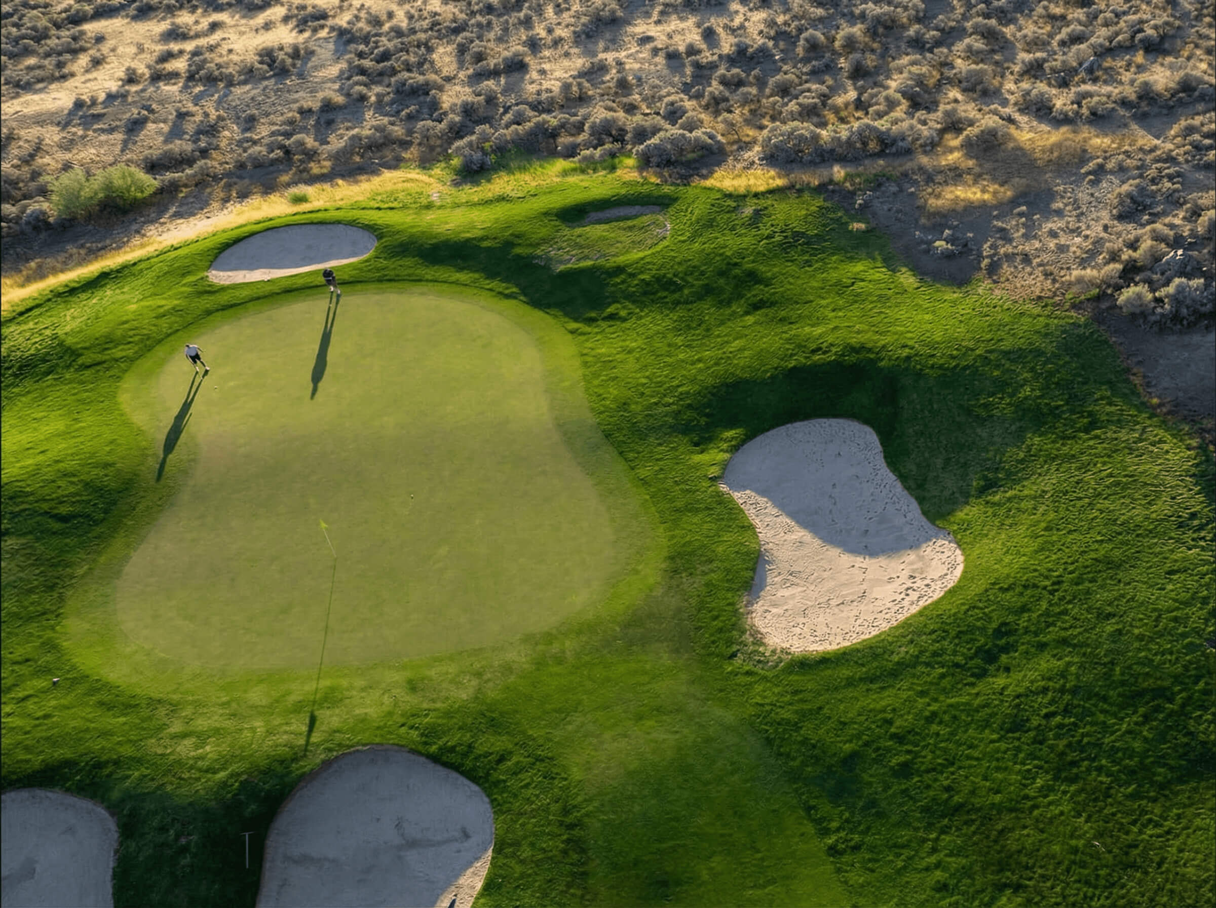 Aerial view of Bighorn Golf Kamloops green with surrounding bunkers and desert landscape edge